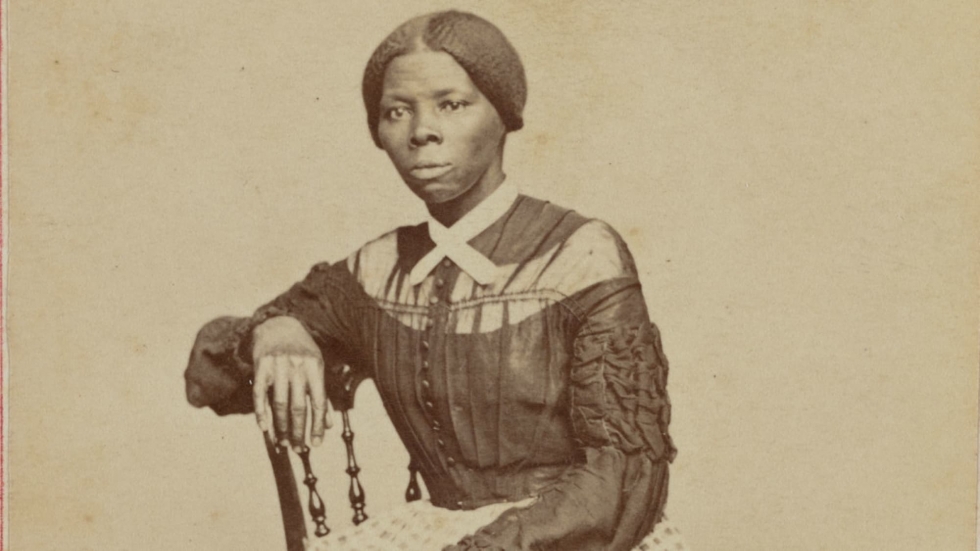 Sepia portrait of Harriet Tubman seated on a wooden chair.